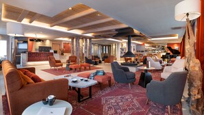 A spacious lobby with a reception desk, comfortable seating areas, a piano, and a bar. - MGM Hôtels & Résidences – Résidence Akoya (Les Avanchers-Valmorel)