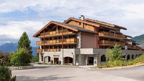Un hotel de varios pisos con fachada de piedra, balcones de madera y una recepción.