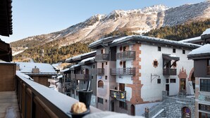 A mountain resort with snow-covered buildings, wooden balconies, and a view of snow-capped mountains. - MGM Hôtels & Résidences – Résidence Akoya (Les Avanchers-Valmorel)