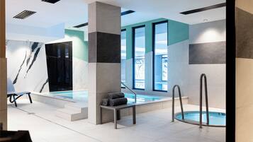 A modern indoor pool area with a seating area, a bench, and a pool with steps leading into it.
