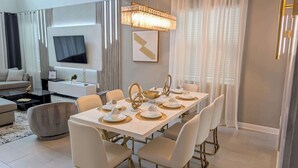A modern dining area with a long table set for six, gold accents, and a contemporary chandelier. - 8955-Luxury 5BR Home at Champions Gate Resort (Davenport)