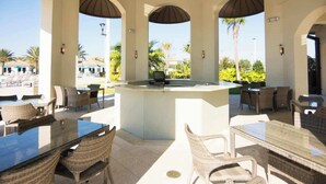 An outdoor dining area with wicker furniture and a central bar. - 8955-Luxury 5BR Home at Champions Gate Resort (Davenport)