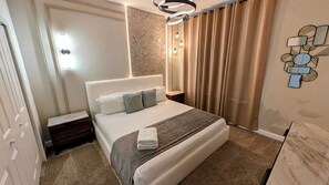 Une chambre d’hôtel avec un lit, des tables de chevet, un luminaire fixé au mur et un rideau.