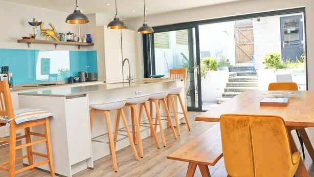A modern kitchen with a central island, bar stools, and pendant lighting. - Stylish townhouse in Padstow (Padstow)