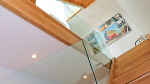 A modern interior with wooden ceiling beams, a glass partition, and a wall-mounted artwork. - Stylish townhouse in Padstow (Padstow)