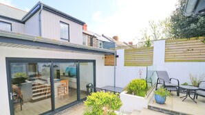 A modern house with a glass door leading to a patio area. - Stylish townhouse in Padstow (Padstow)