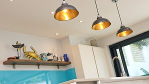 A kitchen with pendant lighting, a white cabinet, and a window with a view. - Stylish townhouse in Padstow (Padstow)