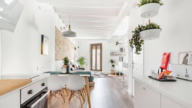 A modern kitchen with white cabinetry, a wooden countertop, and a dining area with a table and chairs. - Unik Vacation Circus (Tarragona)
