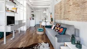 A modern living room with a grey sofa, a white entertainment unit, and a brick accent wall. - Unik Vacation Circus (Tarragona)