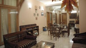 A spacious living room with a sofa, chairs, a coffee table, and a dining area with a table and chairs. - Room-home Stay Bed And Break Fast (New Delhi)