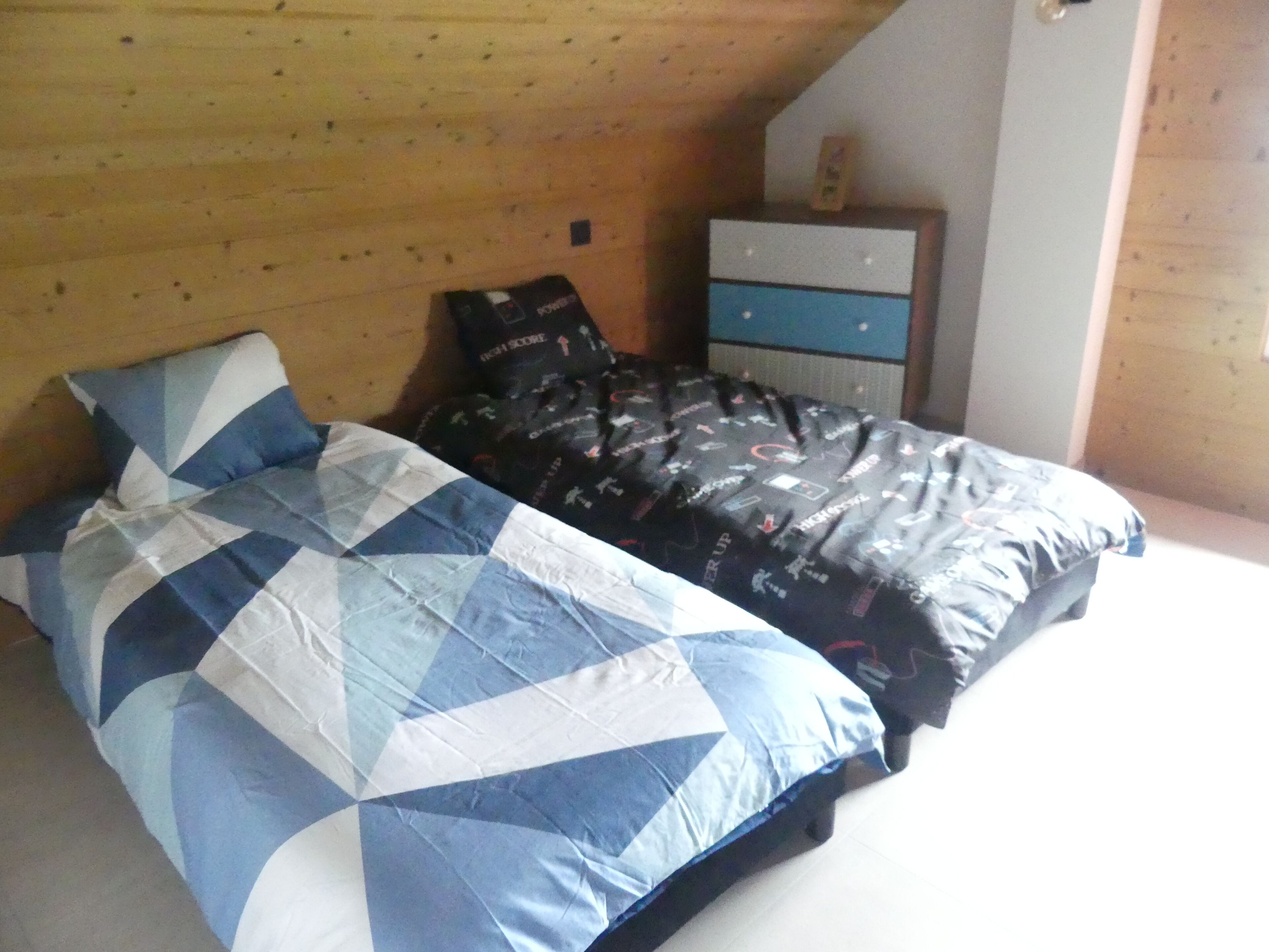A bedroom with a bed, a dresser, and a wooden ceiling.