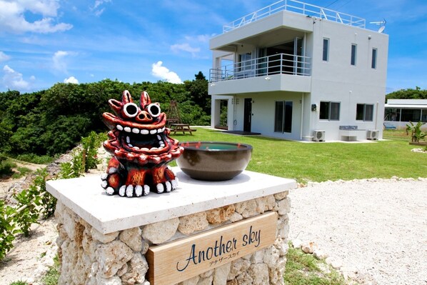 A modern building with a stone base and a sign reading "Another sky". - Another Sky Ishigaki Island (Ishigaki)