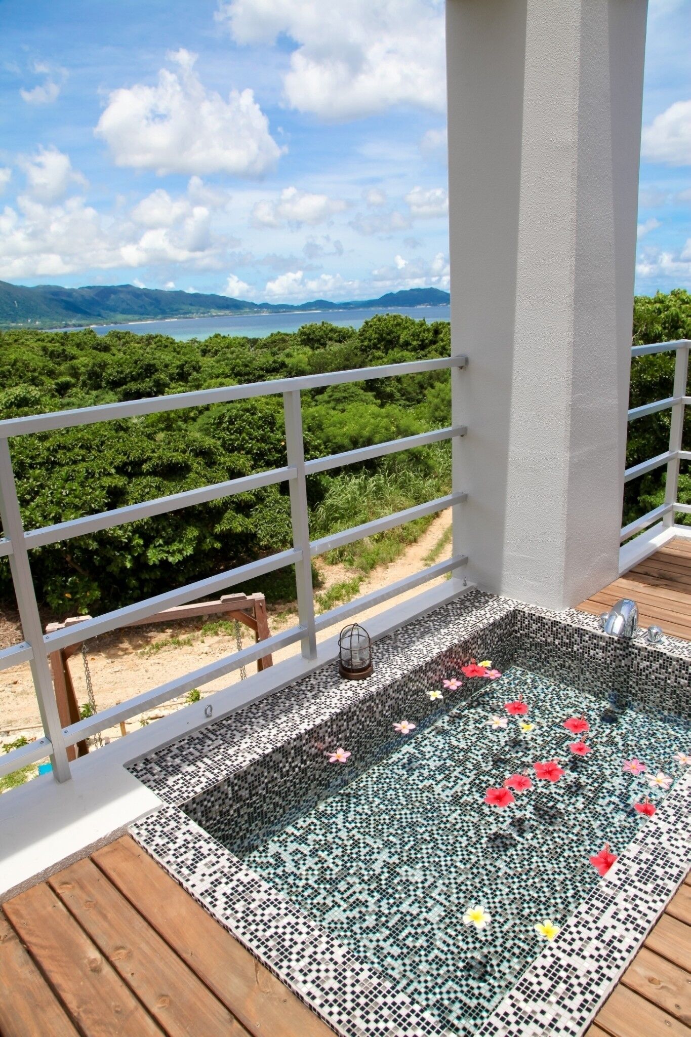 A balcony with a view of a mountainous landscape, a tiled floor, and a metal railing.
