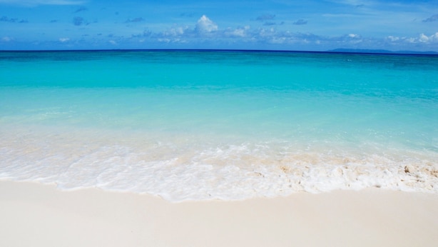 A beach with clear turquoise water and white sand.
