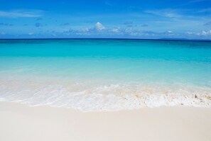 Une plage à l’eau turquoise et limpide et au sable blanc.