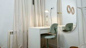 A room with a white desk, a chair, a desk lamp, a mirror, and a radiator. - Charming one-bedroom apartment in Madrid, close to the Tetuán metro (Madrid)