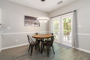 A dining area with a round wooden table and four chairs, a pendant light, and a cityscape painting on the wall. - 5-Bed Gem Close to Duluth Fun-Sleeps 16 (Duluth)