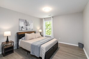 A bedroom with a bed, two bedside tables, a nightstand, a window with curtains, and a ceiling light. - 5-Bed Gem Close to Duluth Fun-Sleeps 16 (Duluth)