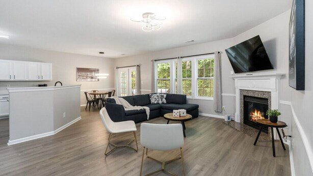 A modern living room with a sectional sofa, a fireplace, and a dining area with a table and chairs. - 5-Bed Gem Close to Duluth Fun-Sleeps 16 (Duluth)