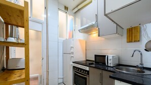 Una cocina compacta equipada con microondas, estufa, lavaplatos y estanterías de madera.