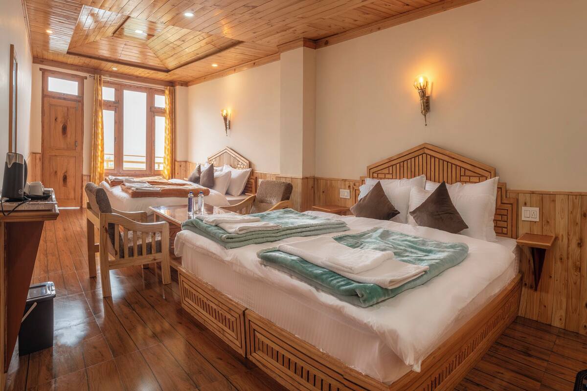 Ein Zimmer mit Holzboden, zwei Betten, einem Schreibtisch und einem Stuhl.