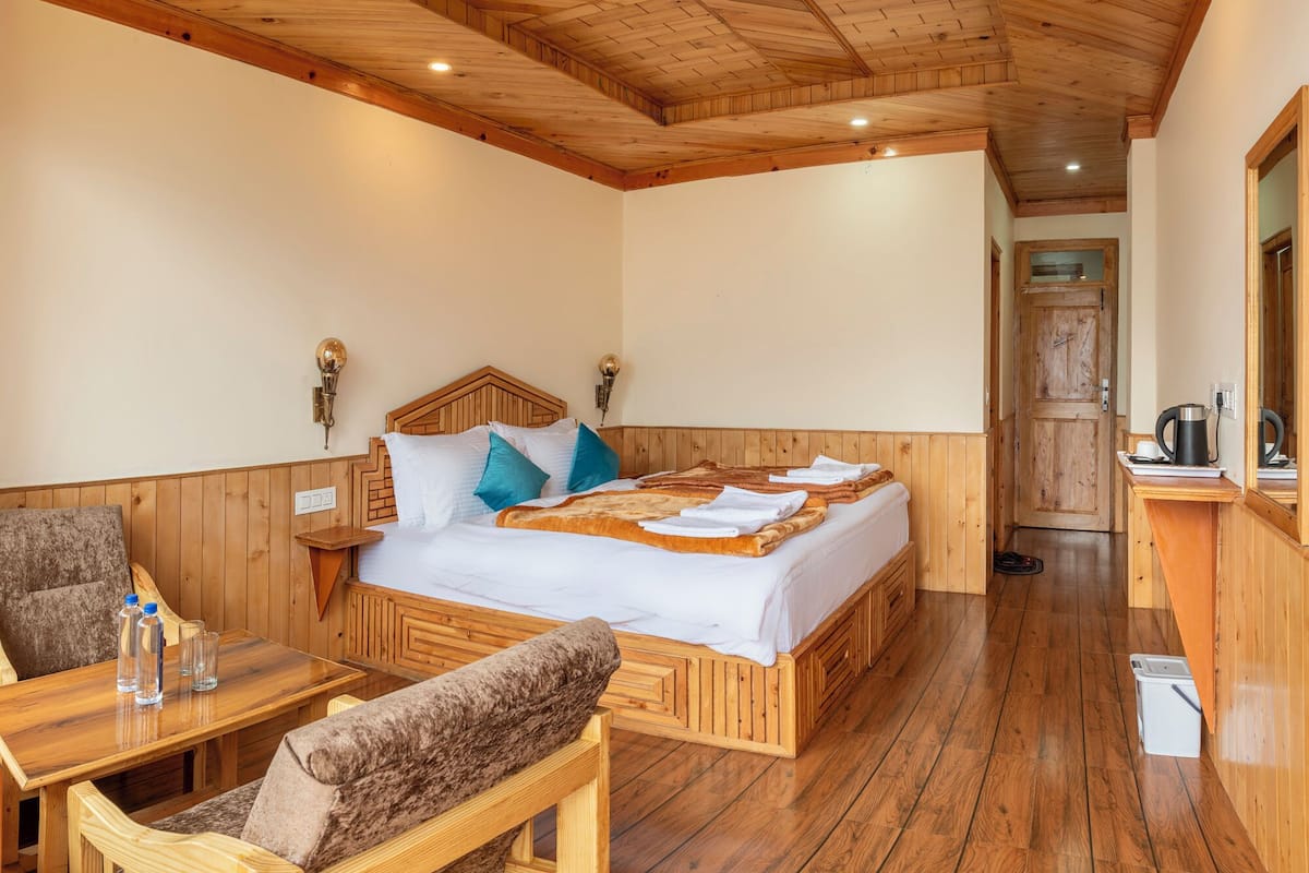 Ein Zimmer mit Holzwänden, einem Bett, einem kleinen Tisch mit Flaschen und einem Stuhl.