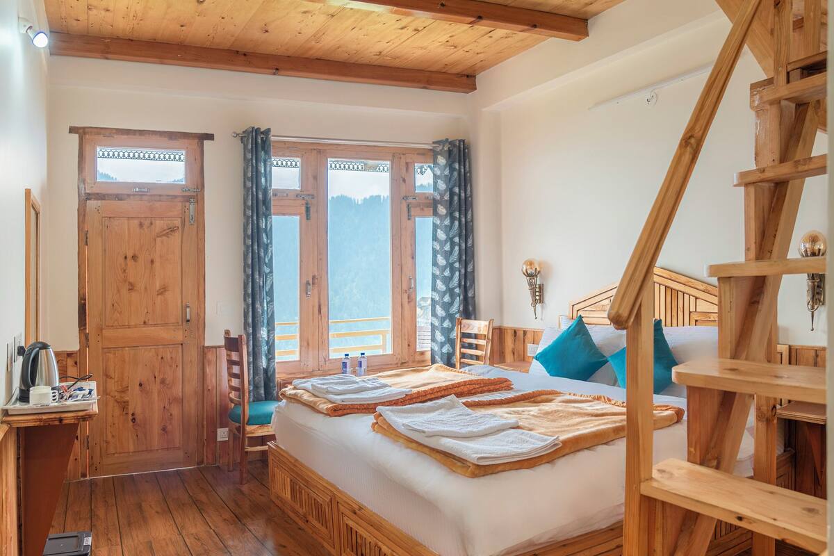 Ein Schlafzimmer in einer Holzhütte mit Bett, Schreibtisch und Treppe.