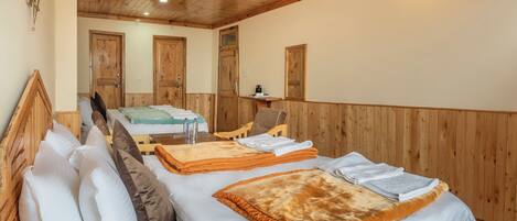A wooden-paneled room with two beds, a wooden headboard, a wall-mounted light fixture, and a wooden door.