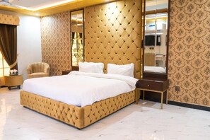 A large, tufted bed with a wooden nightstand and a mirror. - Islamabad Lodges (Islamabad)