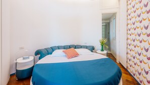 Une chambre à coucher avec un lit aux courbes originales, une table de chevet, une commode et un mur orné d’un motif.