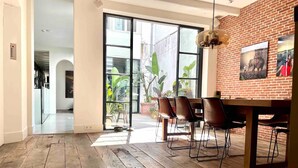 Comedor con pared de ladrillo, ventanas amplias y piso de madera.