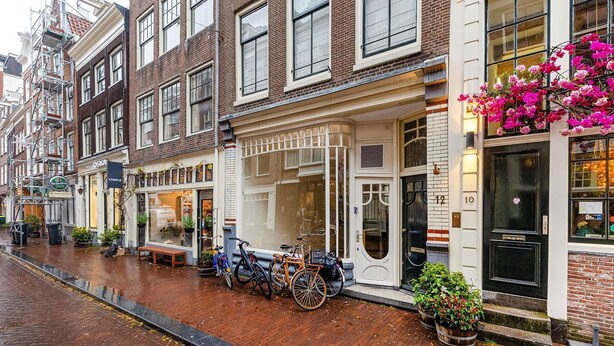 Una hilera de edificios europeos tradicionales con fachada de ladrillo, una tienda con escaparate de cristal y bicicletas estacionadas afuera.