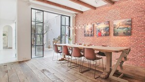Comedor con pared de ladrillo, vigas de madera en el techo y una gran mesa con sillas.
