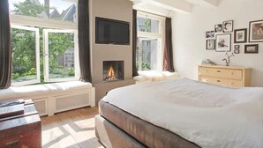 Un dormitorio con una cama grande, una chimenea y un televisor montado en la pared.