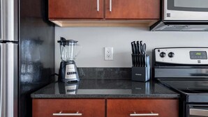 A kitchen with wooden cabinets, a blender, a knife block, and a stove. - Luxury Downtown Apartment (Columbus)