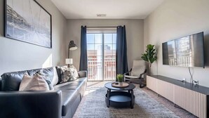 A modern living room with a sofa, a coffee table, and a TV. - Luxury Downtown Apartment (Columbus)