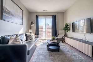 A modern living room with a sofa, a coffee table, and a TV. - Luxury Downtown Apartment (Columbus)