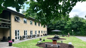A building with outdoor seating and a fire pit area. - Skovly (Viborg)