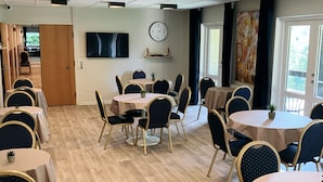 A dining area with round tables and chairs, a clock on the wall, and a door leading to another room. - Skovly (Viborg)