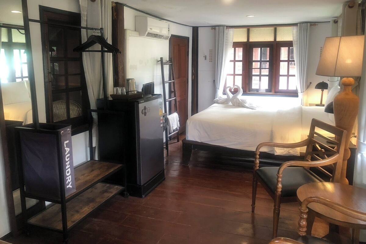 Una habitación de hotel con cama, escritorio, computadora, armario y ventana con cortinas.
