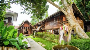 A traditional wooden house with a porch, surrounded by lush greenery and a small pond. - Pastela Doi Saket Villa & Spa (Doi Saket)