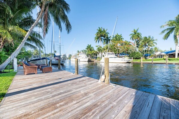 A wooden dock with lounge chairs, a marina with boats, and palm trees. - The Riverside Retreat #2 (Fort Lauderdale)