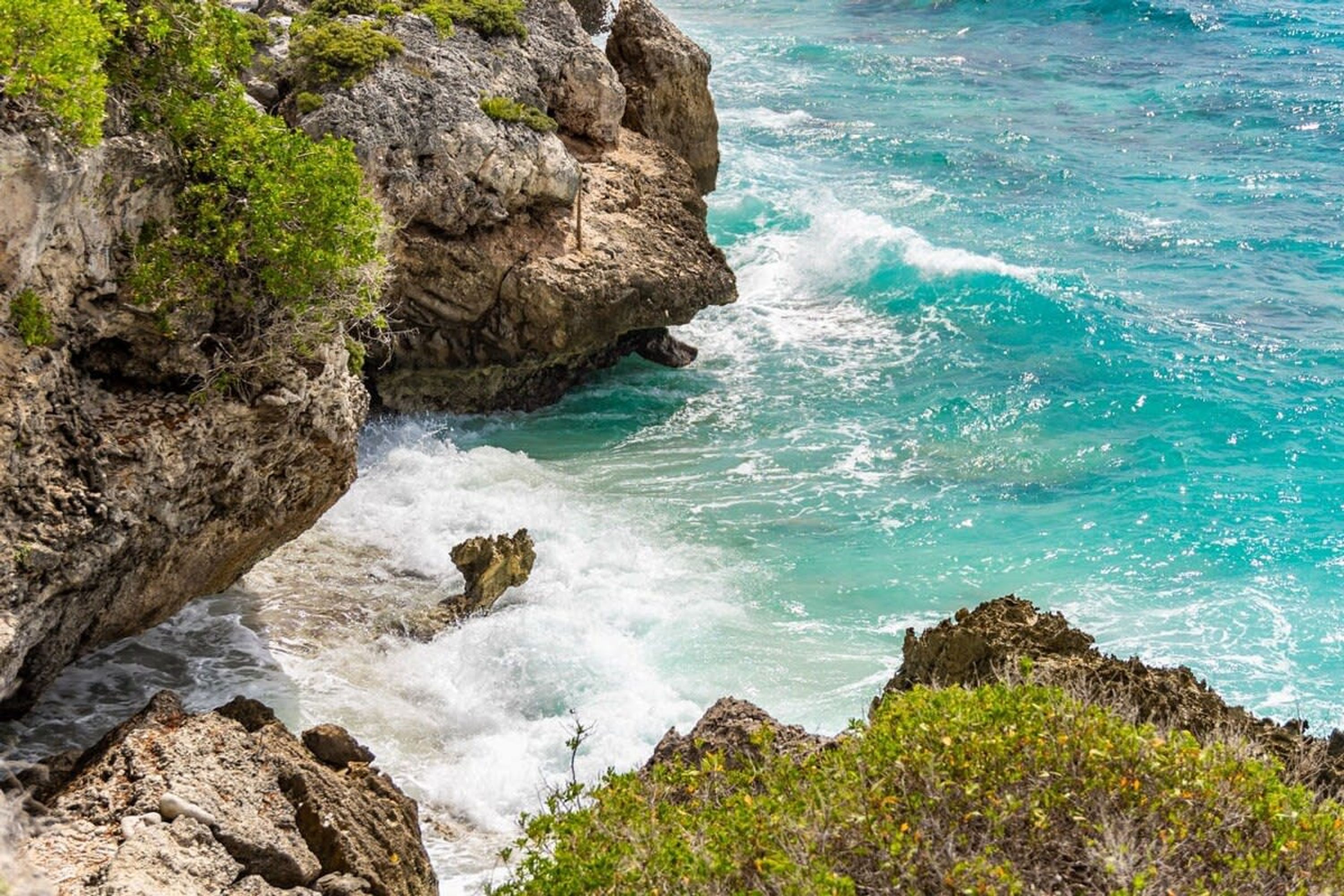 A coastal landscape with rocky cliffs and turquoise ocean waves.