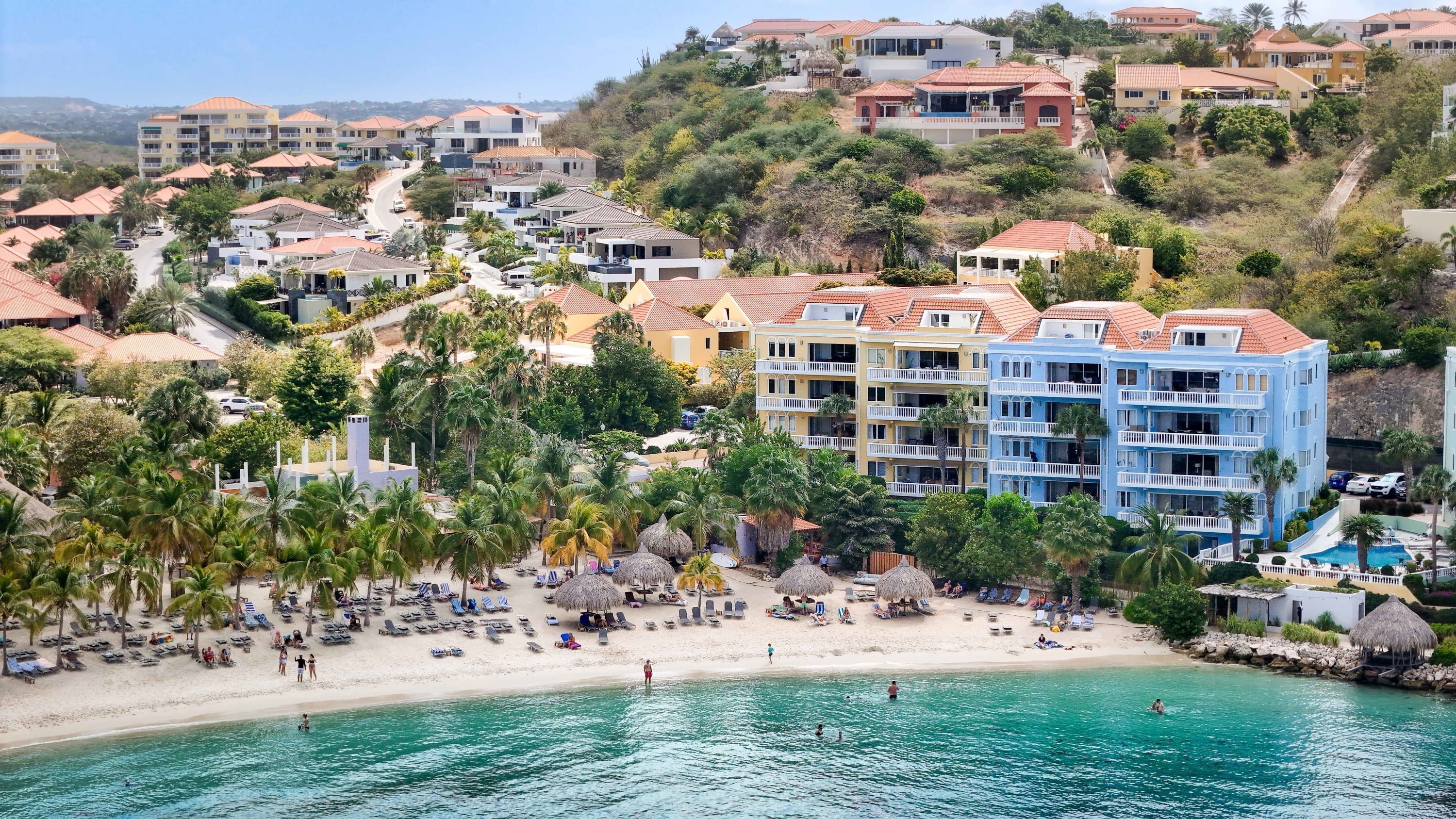 A coastal resort with beachfront villas, a sandy beach, and a pool area.