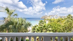 A balcony with a view of a beach, palm trees, and a coastal town. - Serenity by the Seascape Marble Blue Bay Bliss (Sint Michiel)