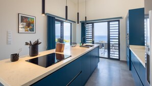 Una cucina moderna con un'isola grande, luci a sospensione e vista all'esterno.