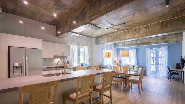 Una cocina moderna con una isla central, sillas de madera y un comedor con mesa y sillas.