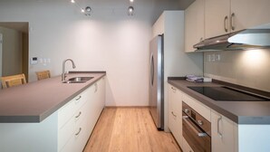 Una cocina moderna con un refrigerador de acero inoxidable, horno empotrado y una encimera con lavamanos.