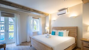 Un dormitorio con una cama de madera, ropa de cama blanca, una mesita de noche y una ventana con cortinas.