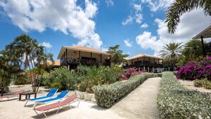 Et resort med en anlagt sti, liggestole og en velholdt have med forskellige planter og blomster.